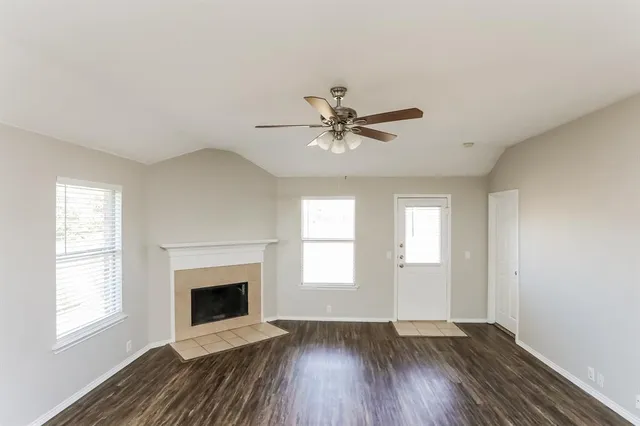 an empty room with windows and fireplace