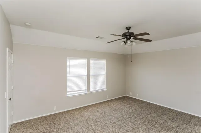 an empty room with window and a ceiling fan