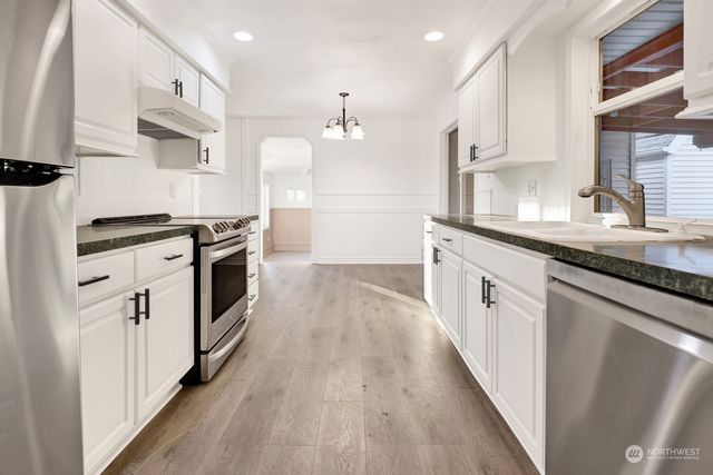 a kitchen with stainless steel appliances granite countertop hardwood floor sink stove and wooden floor