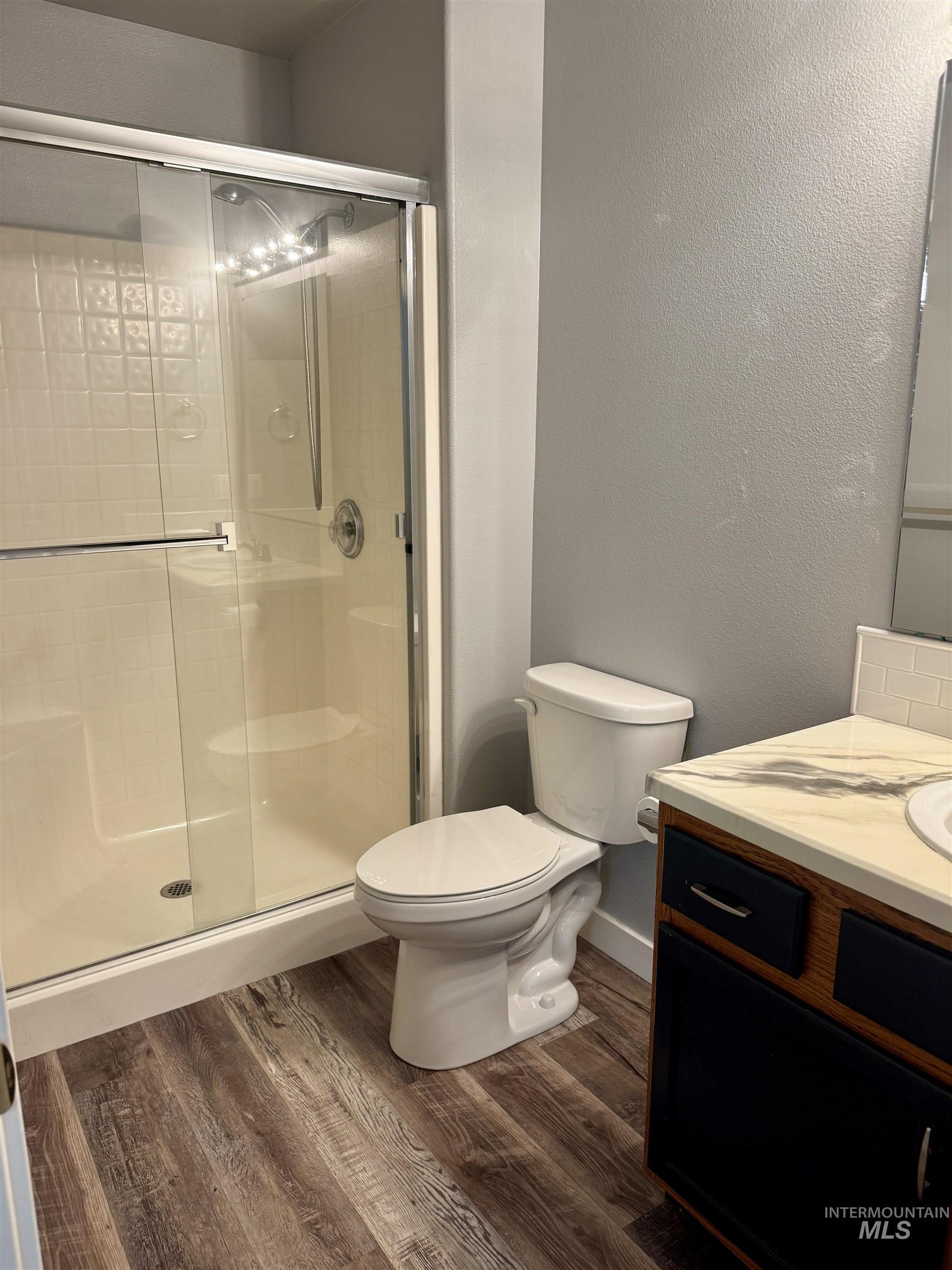 3203 South Capistrano Avenue Boise, ID 83705 - Photo 13 of 30 Bathroom featuring vanity, a textured wall, dark wood-style floors, and a stall shower
