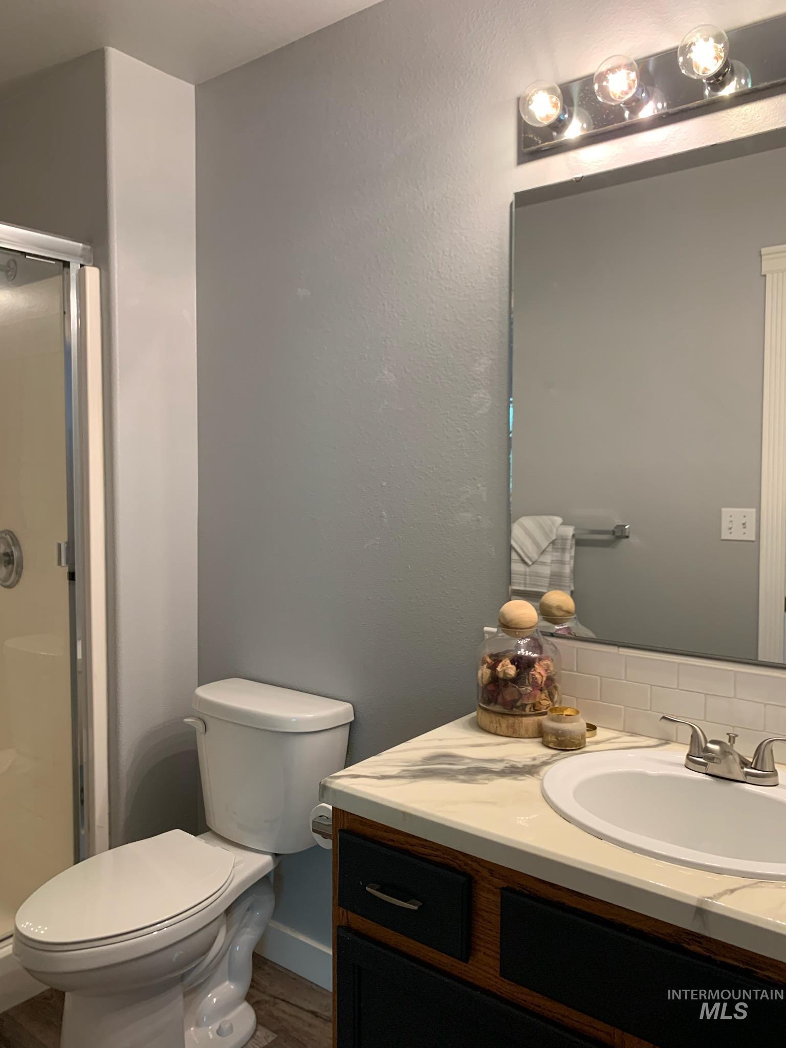 3203 South Capistrano Avenue Boise, ID 83705 - Photo 20 of 30 Bathroom with vanity, a shower stall, a textured wall, backsplash, and dark wood-style flooring