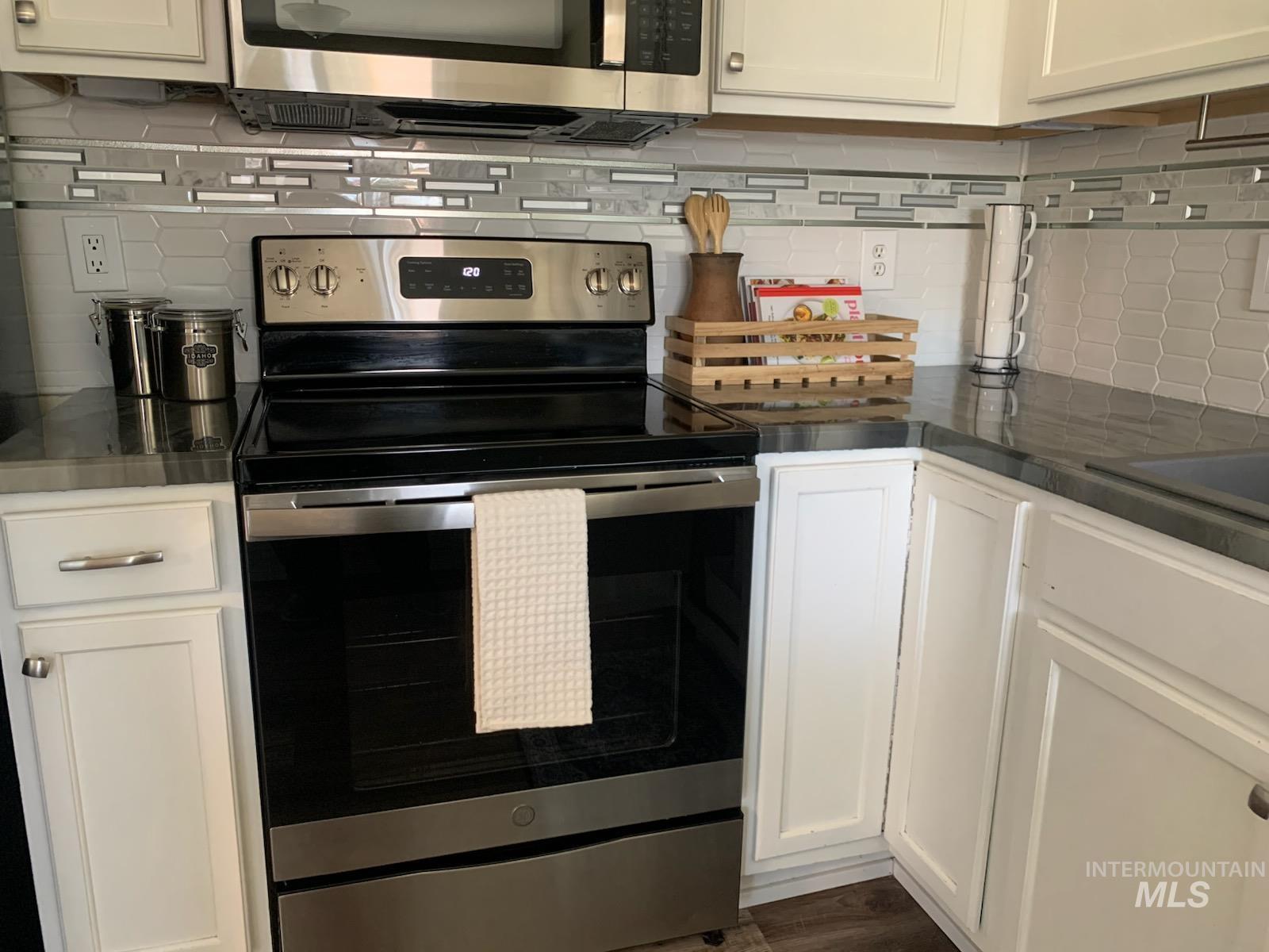 3203 South Capistrano Avenue Boise, ID 83705 - Photo 3 of 30 Kitchen featuring stainless steel appliances, backsplash, dark countertops, and white cabinetry
