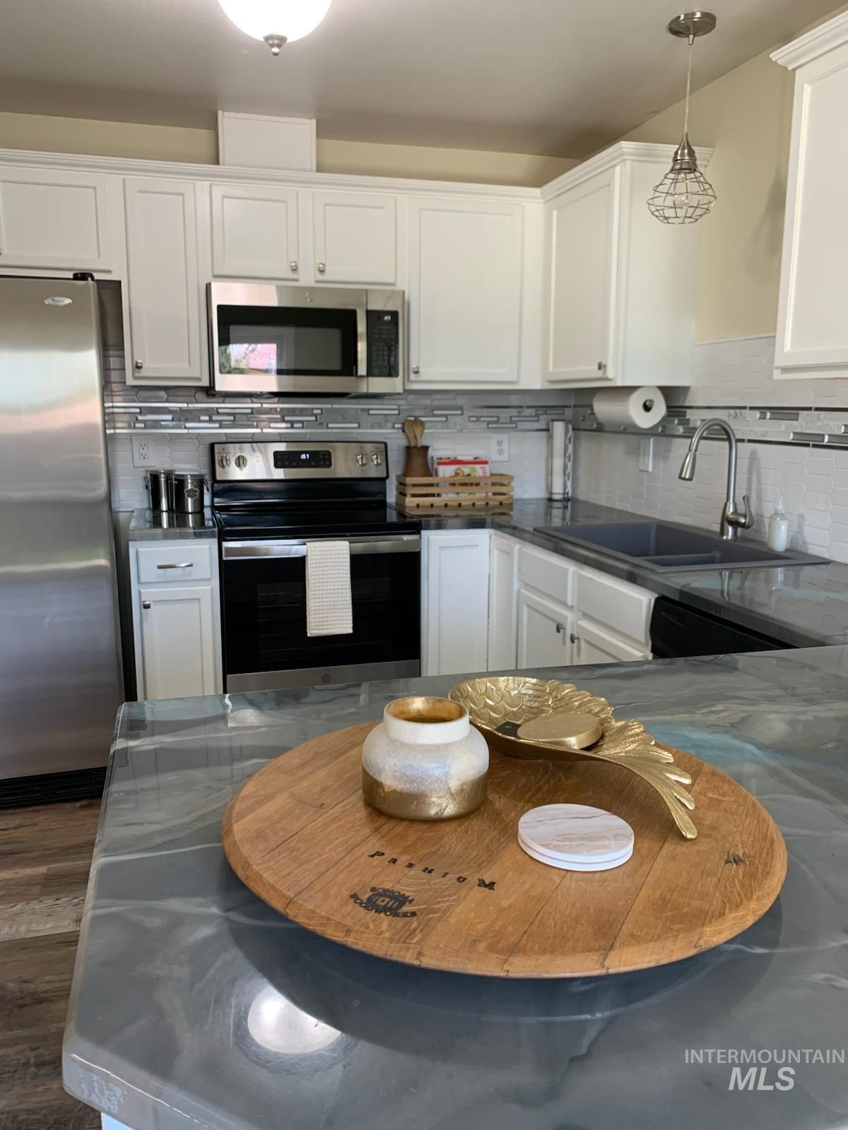 3203 South Capistrano Avenue Boise, ID 83705 - Photo 4 of 30 Kitchen with stainless steel appliances, white cabinets, tasteful backsplash, and decorative light fixtures