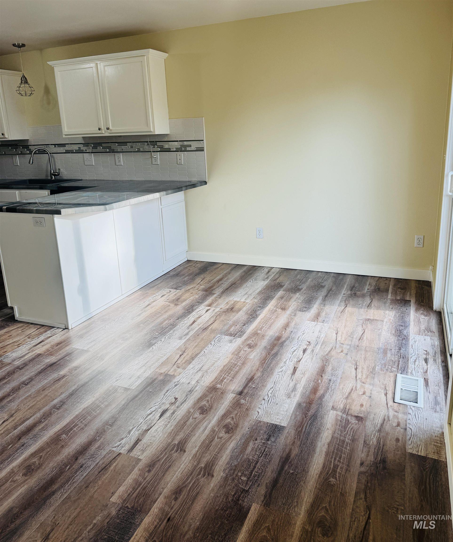 3203 South Capistrano Avenue Boise, ID 83705 - Photo 6 of 30 Kitchen featuring white cabinetry, backsplash, a peninsula, and light wood-style floors
