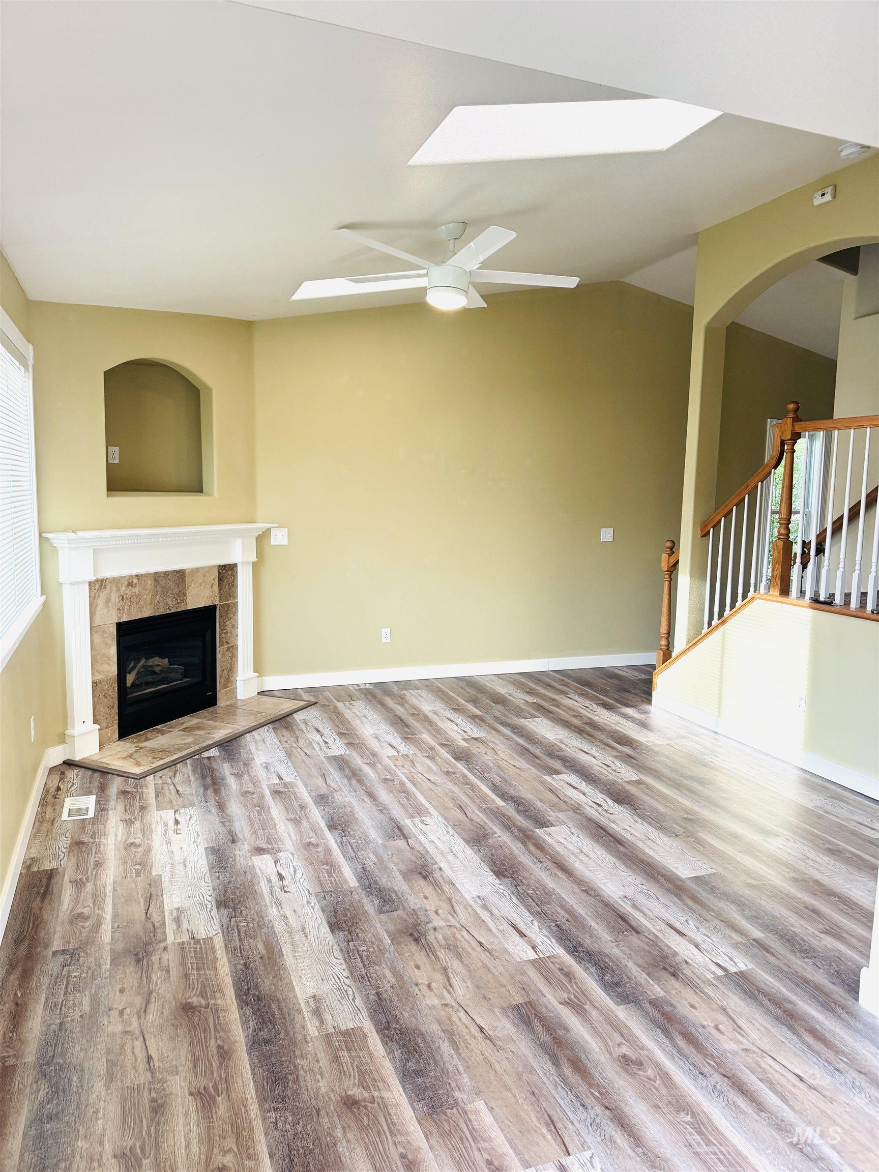 3203 South Capistrano Avenue Boise, ID 83705 - Photo 9 of 30 Unfurnished living room with a ceiling fan, a fireplace, light wood finished floors, and lofted ceiling