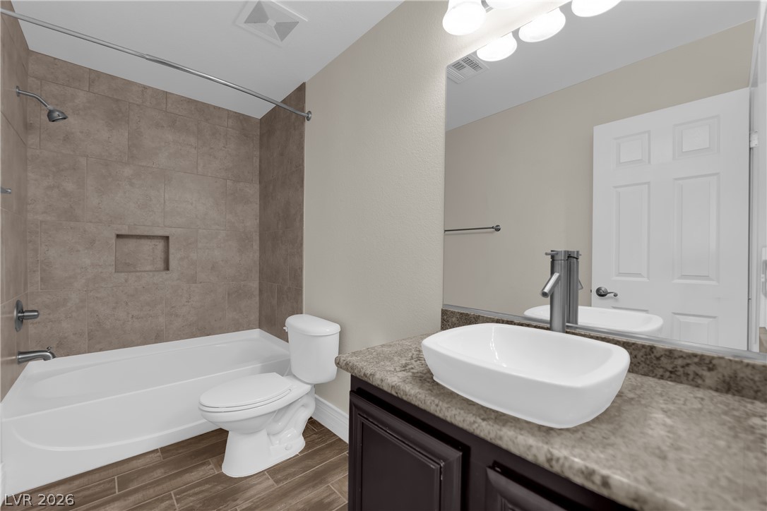 646 Monument Point Street Henderson, NV 89002 - Photo 21 of 44 Modern vessel sink and rich wood-look tile flooring create a refreshing bathroom aesthetic.