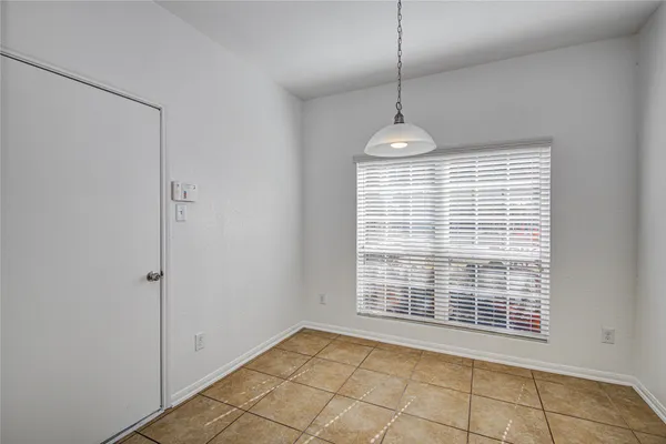 a view of an empty room with a window and chandelier fan