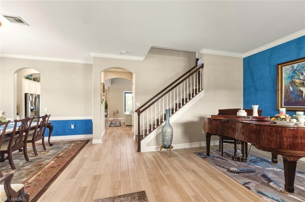 2115 Antigua Lane Naples, FL 34120 - Photo 11 of 41 Foyer entrance with light wood-style floors, arched walkways, ornamental molding, and stairway