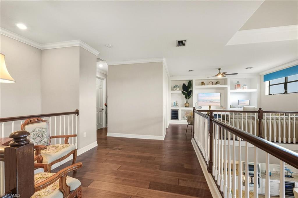 2115 Antigua Lane Naples, FL 34120 - Photo 20 of 41 Hallway with an upstairs landing, dark wood-style flooring, ornamental molding, recessed lighting, and built in shelves