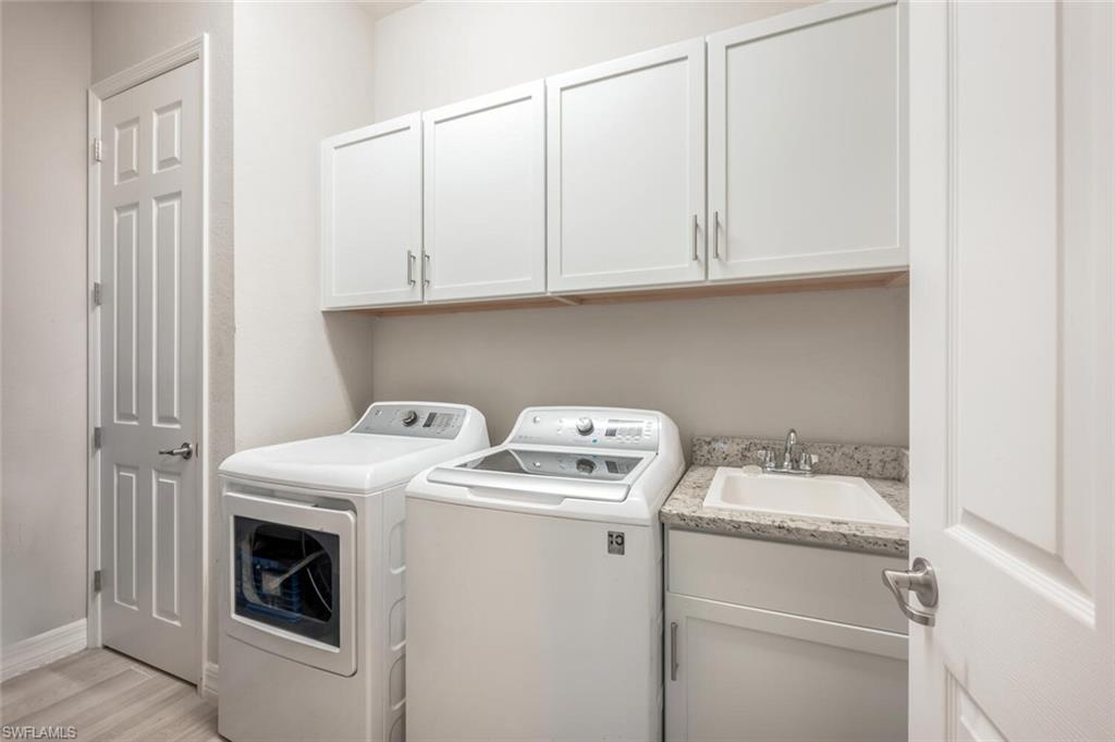 2115 Antigua Lane Naples, FL 34120 - Photo 37 of 41 Laundry room featuring cabinet space, washing machine and dryer, and light wood-type flooring