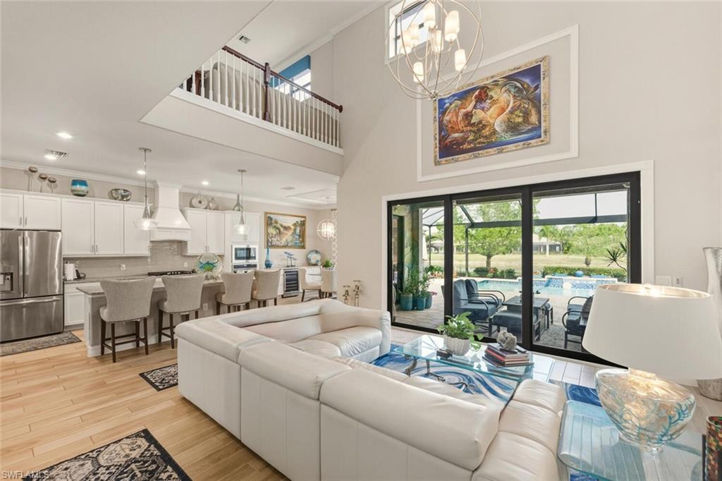 2115 Antigua Lane Naples, FL 34120 - Photo 4 of 41 Living area featuring a chandelier, a high ceiling, light wood-style floors, beverage cooler, and recessed lighting