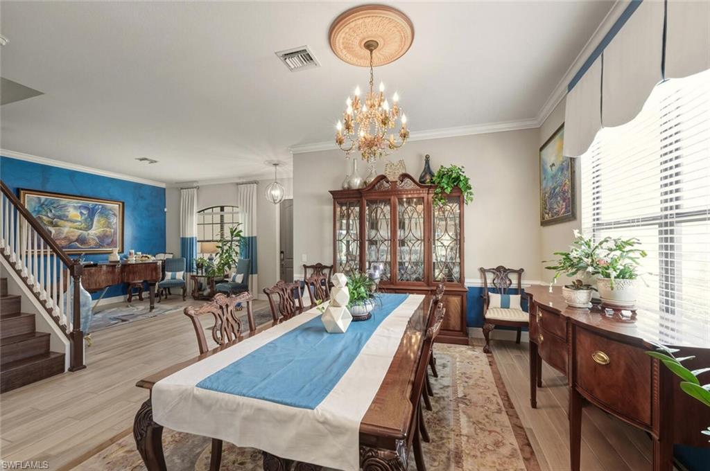 2115 Antigua Lane Naples, FL 34120 - Photo 9 of 41 Dining room with ornamental molding, a chandelier, wood finished floors, next to the living room
