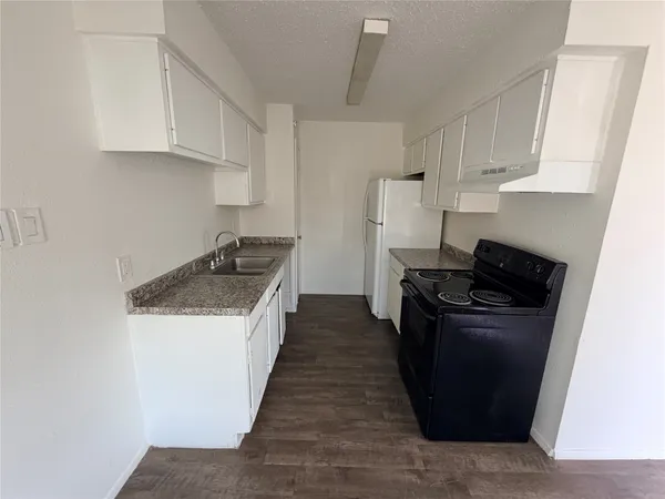 a kitchen with granite countertop a refrigerator stove and sink