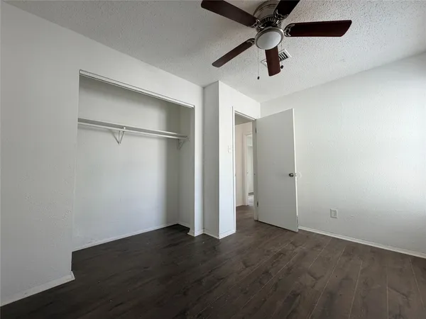 a view of an empty room with a ceiling fan wooden floor and a ceiling fan