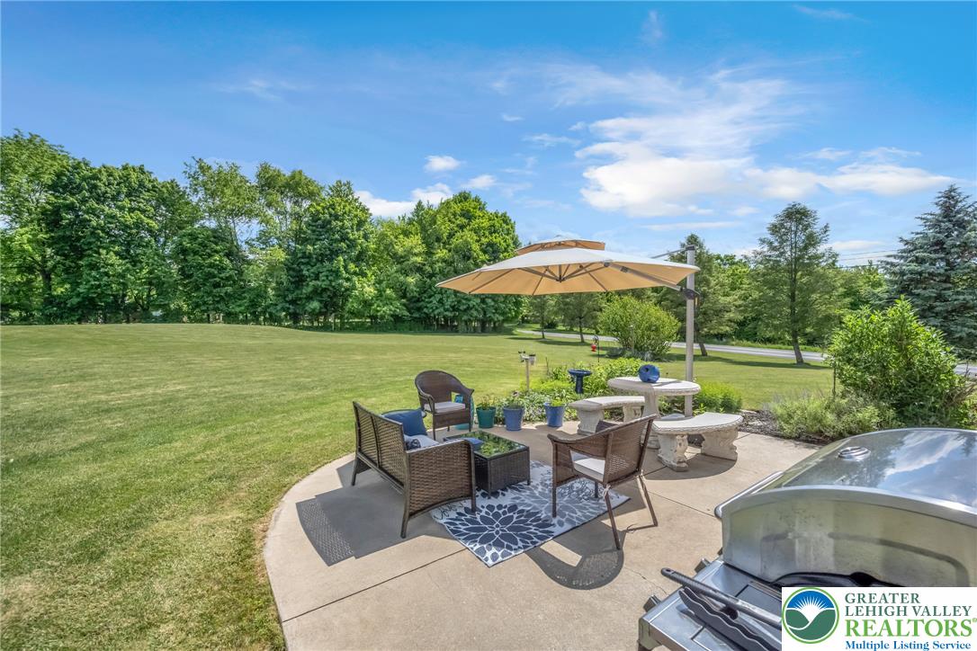 204 Bushkill Ridge Road Wind Gap, PA 18091 - Photo 43 of 48 A generous concrete patio provides a comfortable outdoor living space with abundant green lawn stretching to a wooded backdrop.