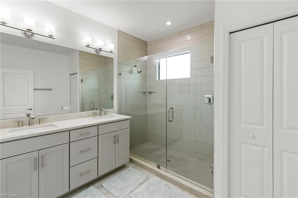 7515 Morgan Way Naples, FL 34119 - Photo 15 of 34 a bathroom with a shower sink and mirror