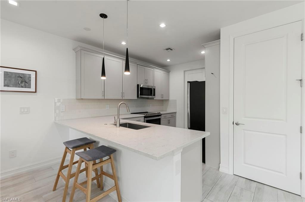 7515 Morgan Way Naples, FL 34119 - Photo 8 of 34 a kitchen with a sink a refrigerator and chairs