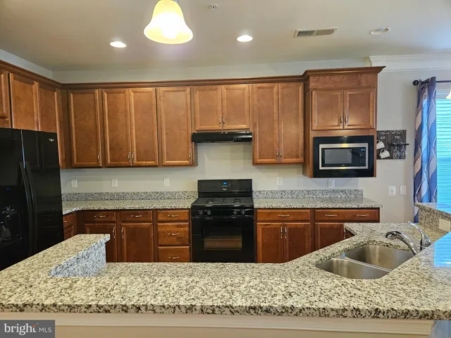a kitchen with stainless steel appliances granite countertop a stove a sink and a microwave