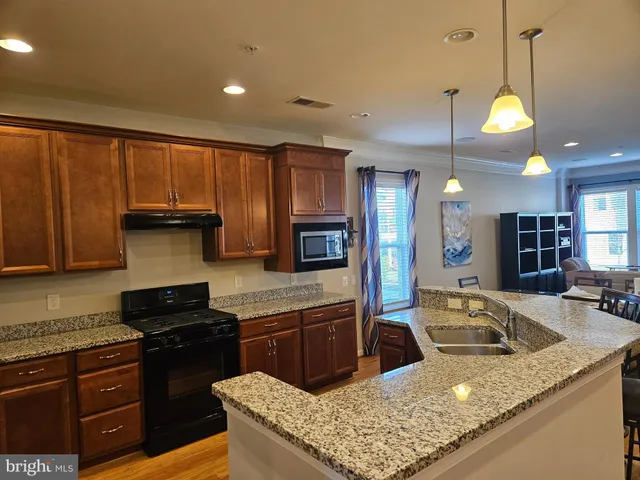 a kitchen with stainless steel appliances granite countertop a sink a stove and a wooden cabinets