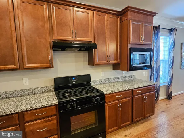 a kitchen with granite countertop wood cabinets and stainless steel appliances