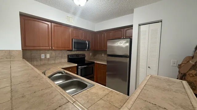 a kitchen with granite countertop wooden cabinets a refrigerator and a sink