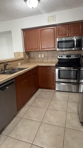 a kitchen with kitchen island granite countertop a stove a sink and a microwave