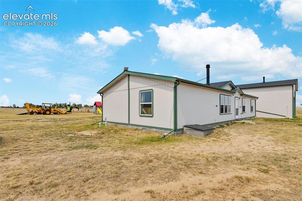 1350 South Calhan Highway Yoder, CO 80864 - Photo 43 of 45 Single-story property with light-colored siding and dark green trim, featuring multiple windows