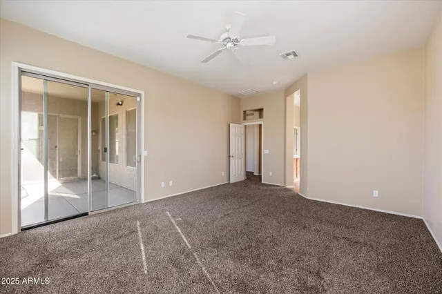 an empty room with closet and a ceiling fan