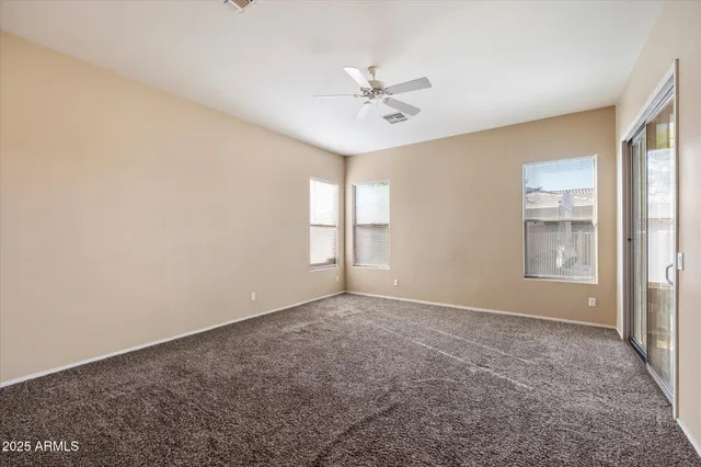 an empty room with windows and fan