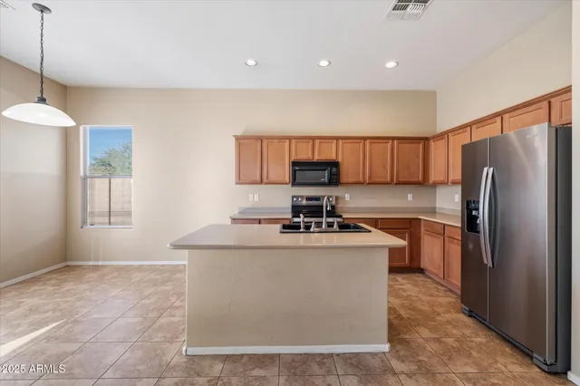 a kitchen with stainless steel appliances granite countertop a stove a refrigerator a sink and a microwave