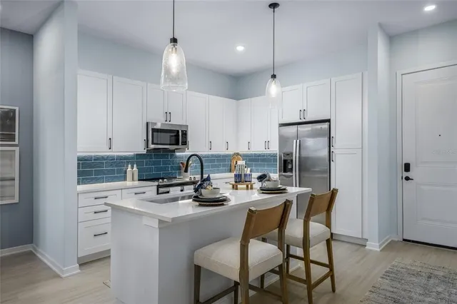 a kitchen with stainless steel appliances granite countertop a sink stove refrigerator and cabinets with wooden floor