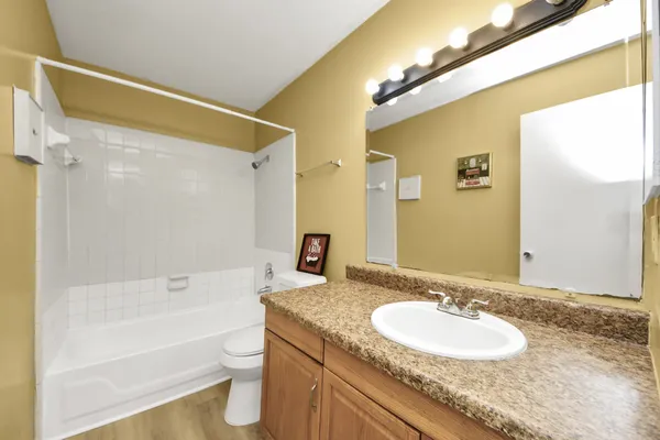 a bathroom with a granite countertop sink a toilet a mirror a bathtub and shower