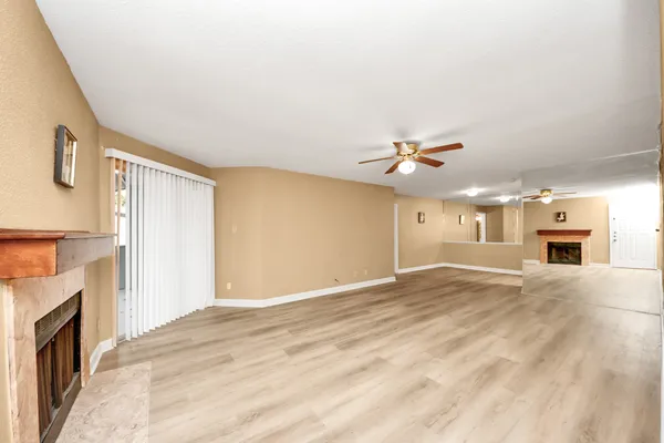 a view of a livingroom with a fireplace a ceiling fan and wooden floor