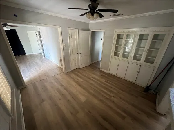 a view of empty room with wooden floor and fan
