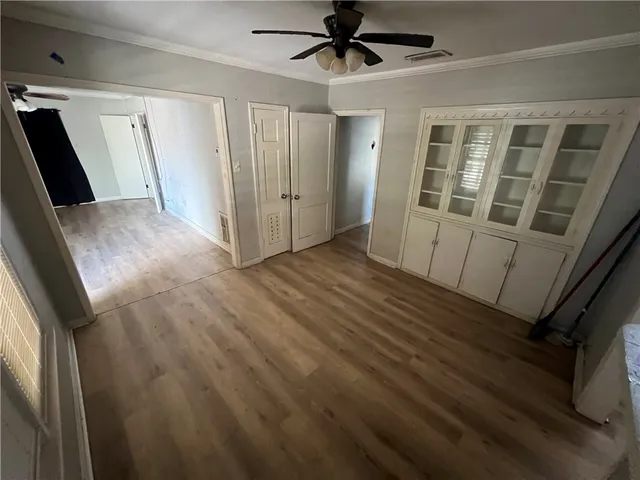 a view of empty room with wooden floor and fan