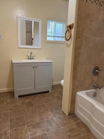 a bathroom with a bathtub sink and mirror
