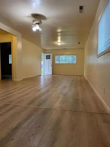 a view of an empty room with window and chandelier fan