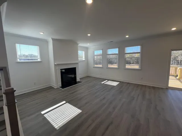 an empty room with windows fireplace and wooden floor
