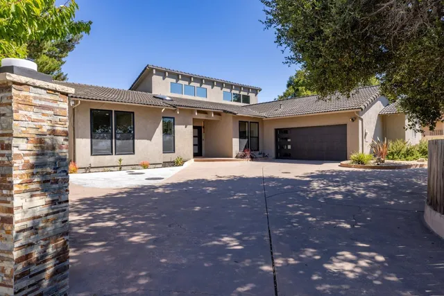 a front view of a house with a yard and potted plants