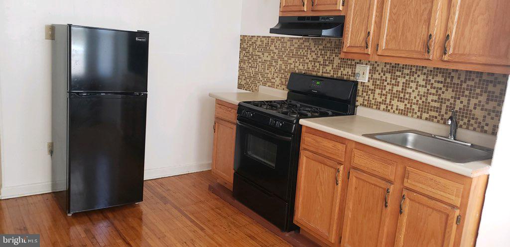a kitchen with granite countertop a refrigerator stove and cabinets