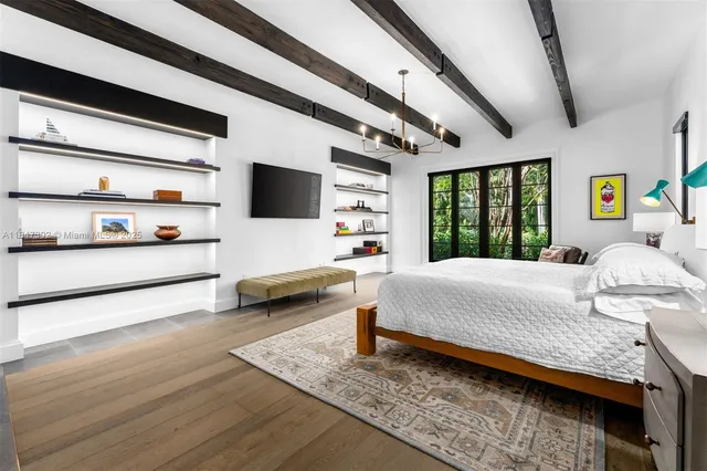 a bedroom with a large bed and a flat tv screen on dresser