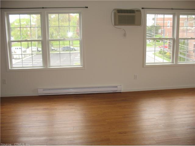 7 New Street, Unit 202 Danbury, CT 06810 - Photo 2 of 10 an empty room with wooden floor and windows