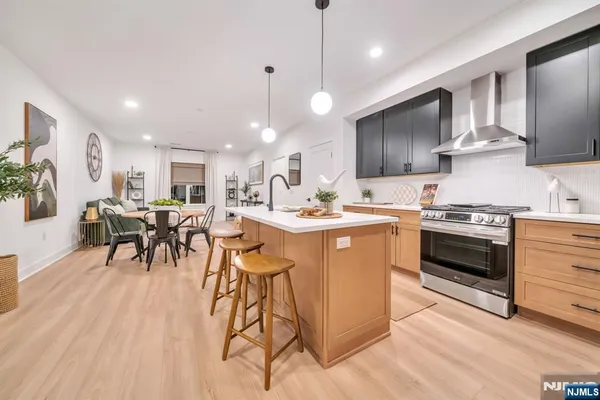a kitchen with stainless steel appliances a stove a sink a refrigerator and chairs