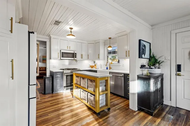 a kitchen with stainless steel appliances granite countertop a refrigerator a stove top oven a sink dishwasher and wooden floor