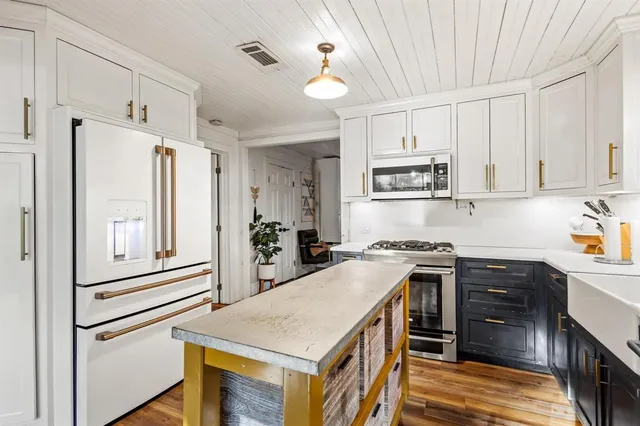 a kitchen with stainless steel appliances granite countertop a stove top oven a refrigerator a sink and dishwasher with white cabinets