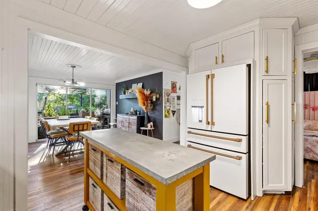 a kitchen with stainless steel appliances a stove a refrigerator a dining table and chairs with wooden floor