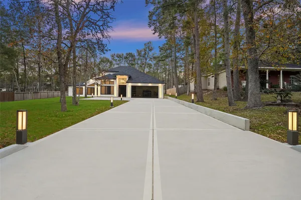 a view of a white house next to a yard with big trees