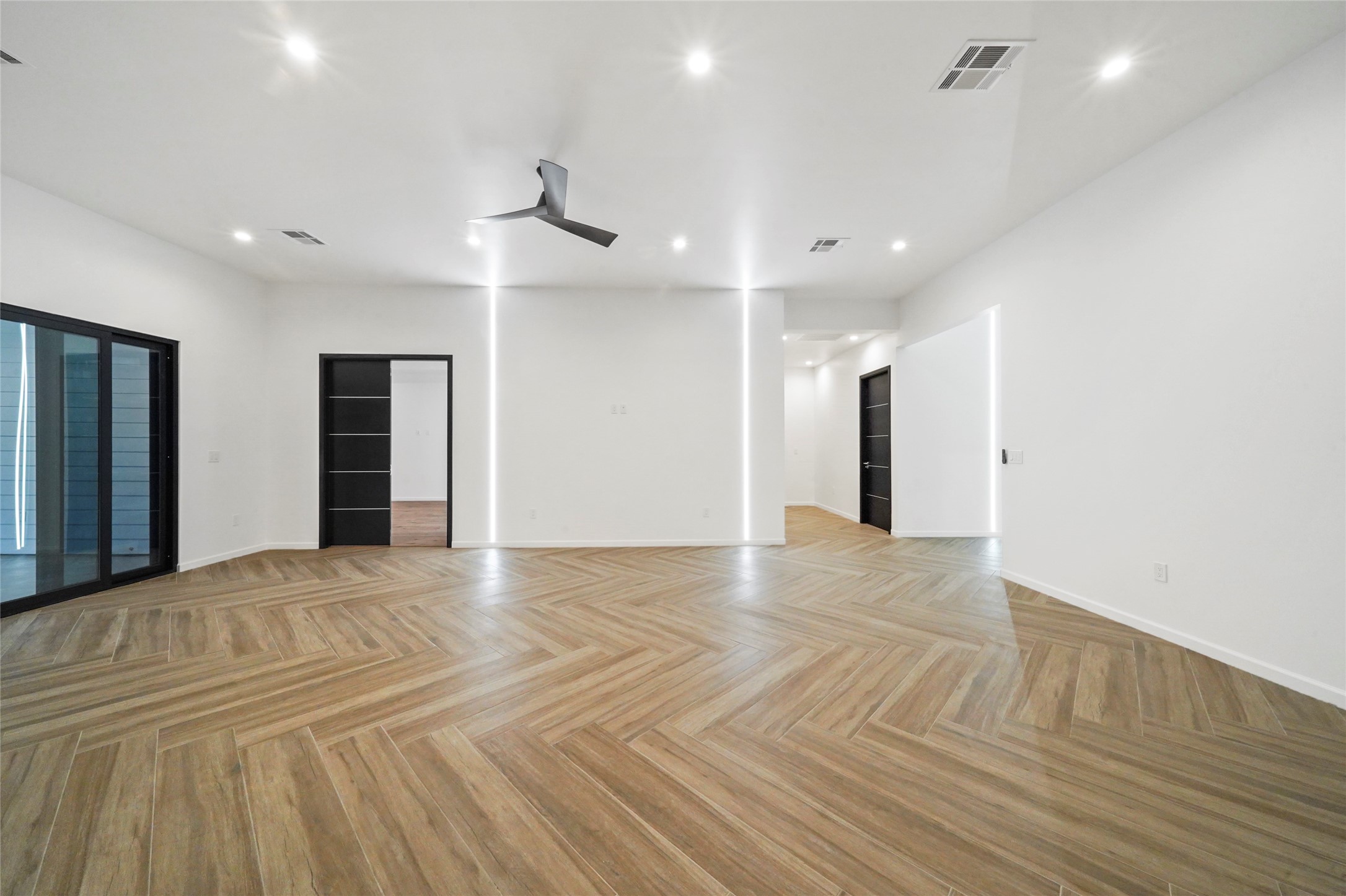 2438 Carriage Lamp Lane Conroe, TX 77384 - Photo 4 of 41 a view of an empty room with wooden floor and a ceiling fan