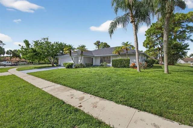 a view of a white house with a big yard and potted plants