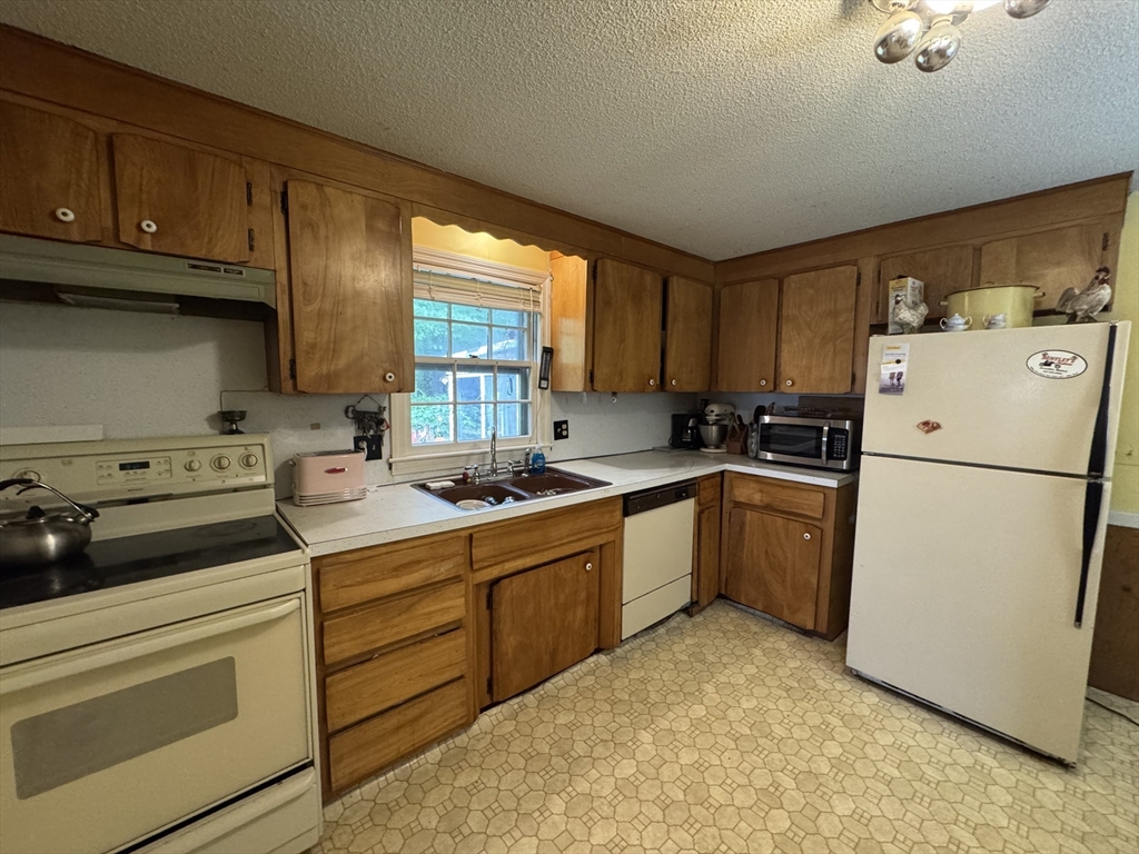 9 Edgewood Avenue Merrimack, NH 03054 - Photo 4 of 13 a kitchen with a refrigerator stove and sink